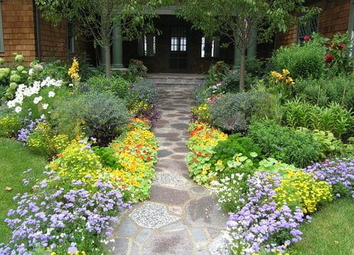 cobblestone walkway leading to home, surrounded by beautiful landscaping