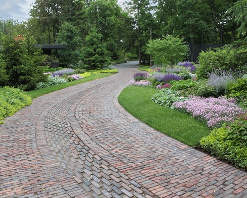 brick and stone path to home surrounded by beautiful landscaping