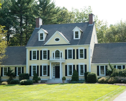 classic home with soft yellow shade and black shutters