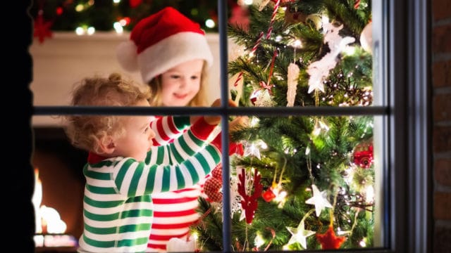 children placing ornaments on a christmas tree